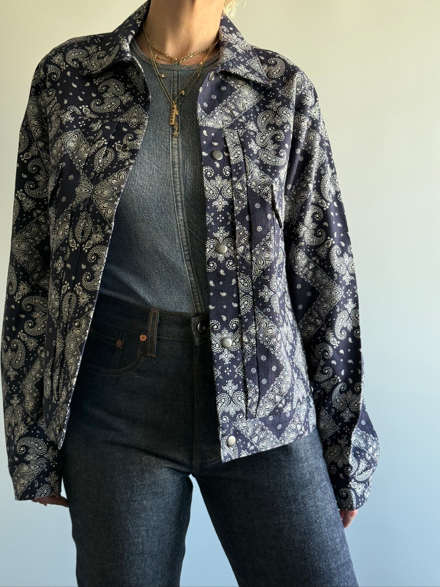Person wearing a navy bandana patterned jacket over a plain shirt with a gradient background